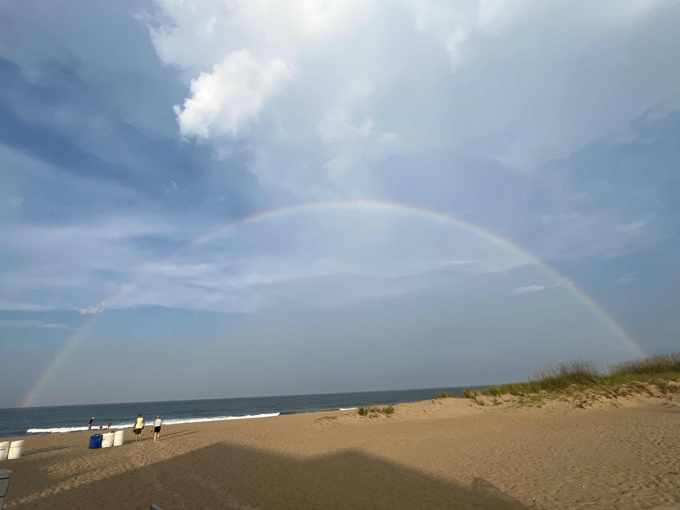 Rainbow arching over Sandbridge Beach with beachgoers